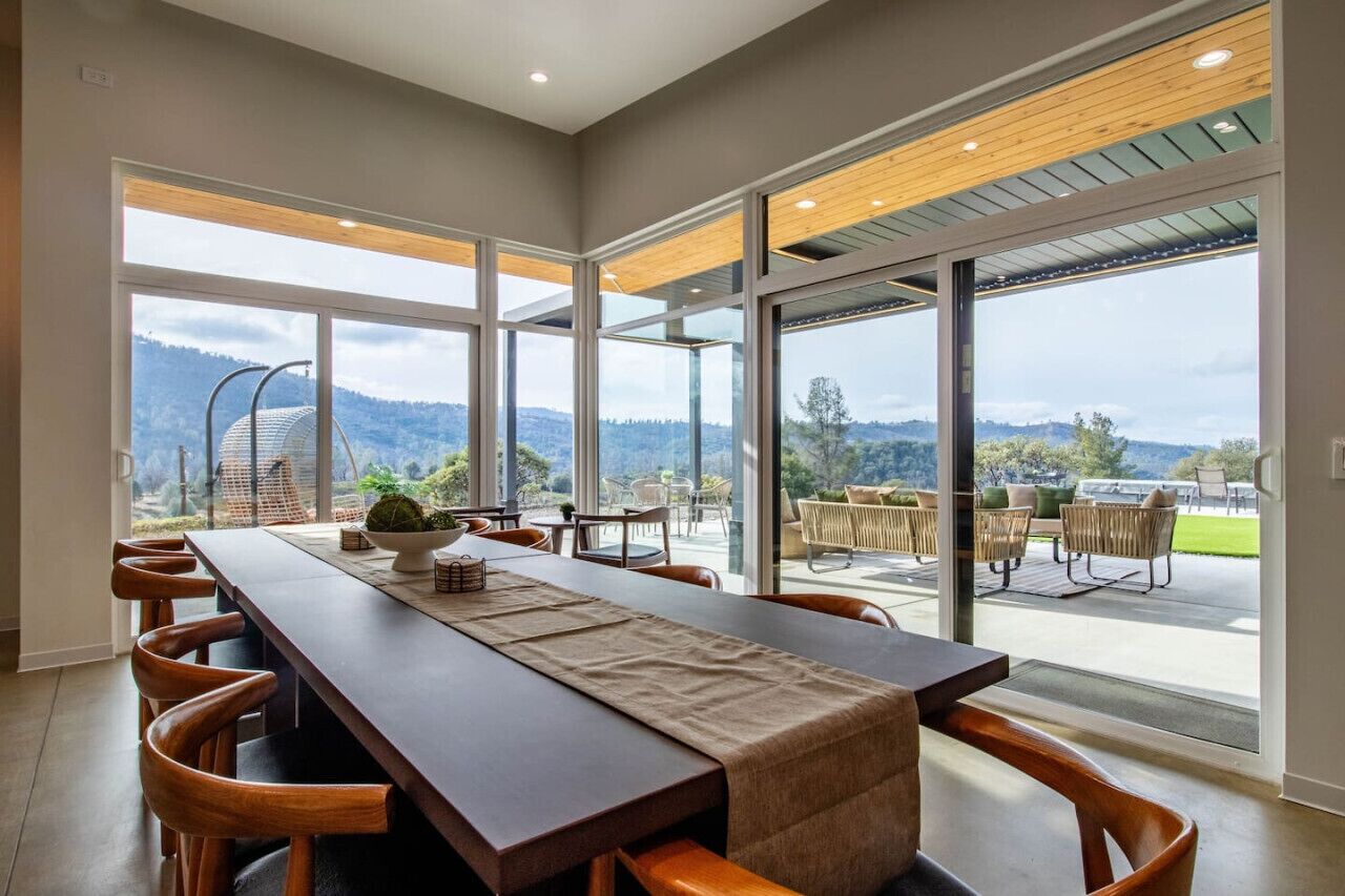 Un comedor con una mesa larga, múltiples sillas y vistas al exterior.