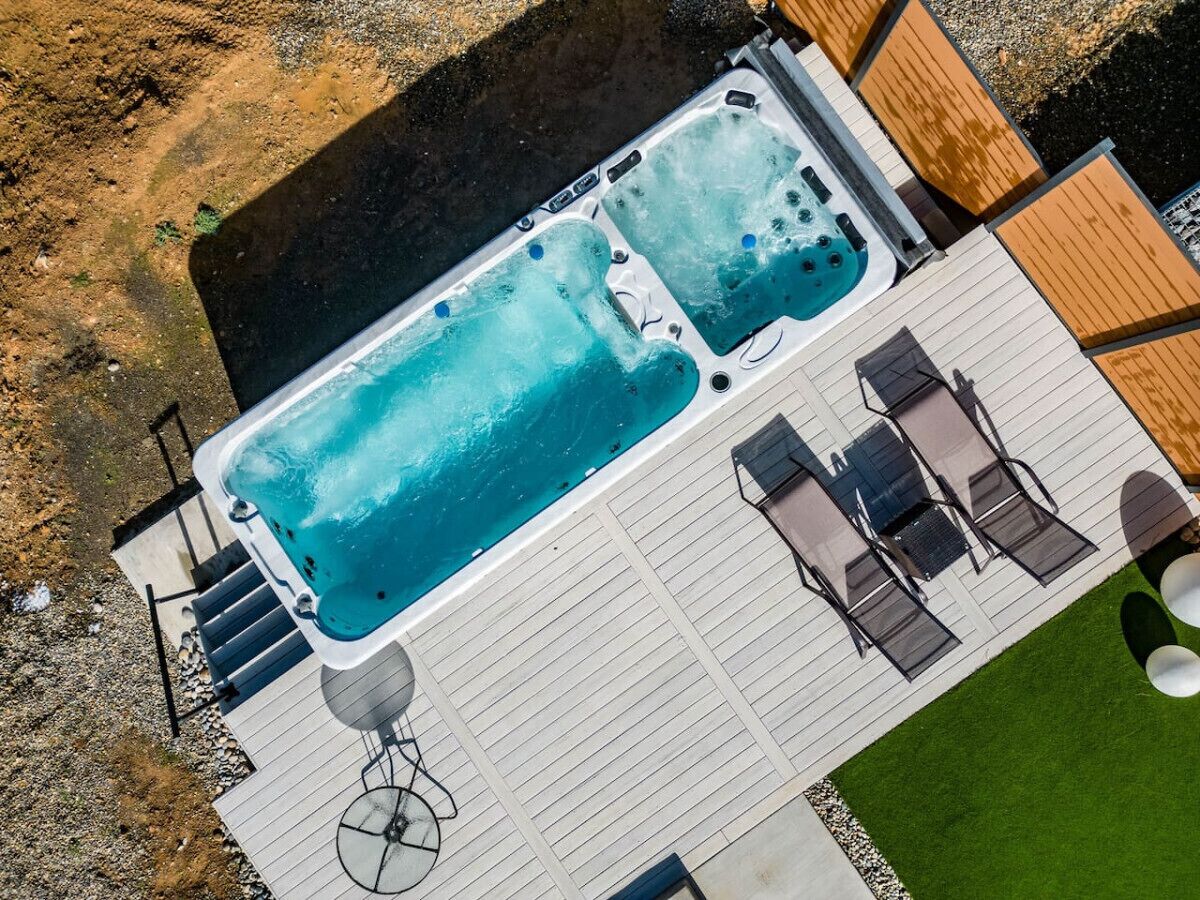 An aerial view of a hot tub area with two hot tubs, a deck, and outdoor seating.