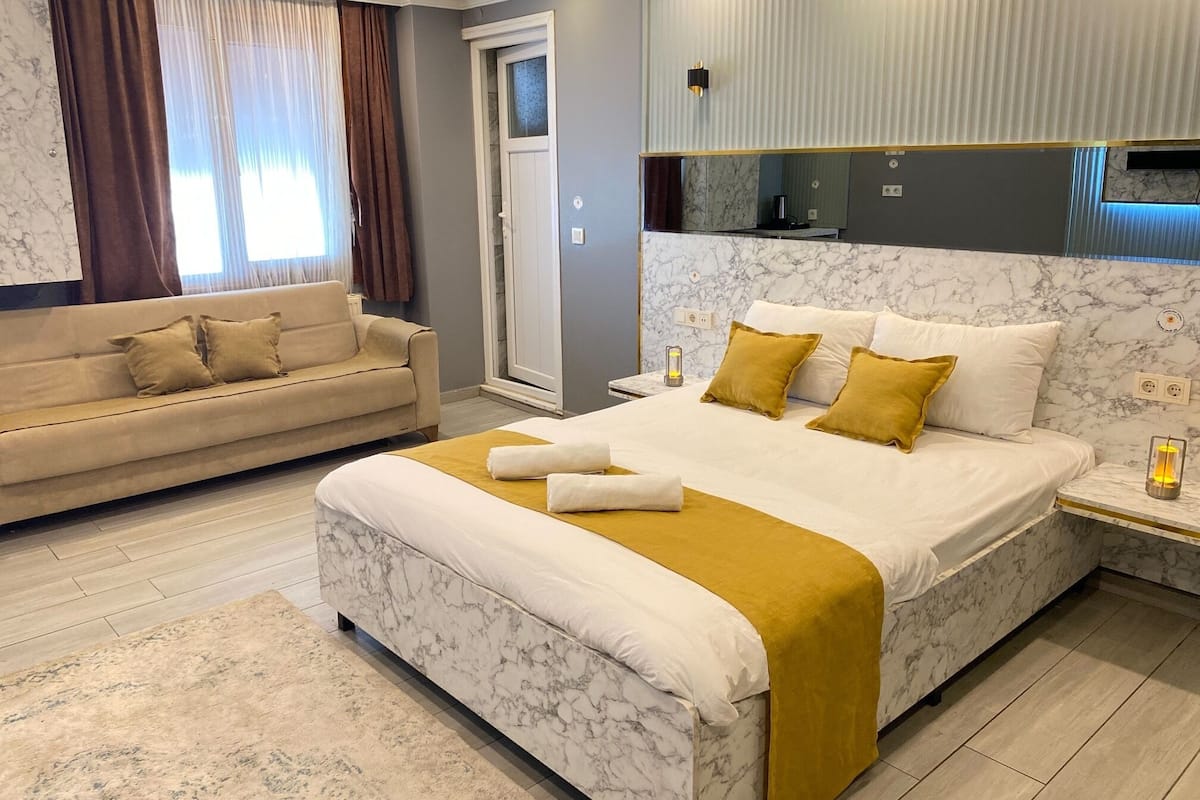 A modern hotel room with a large bed, a sofa, and a bathroom.