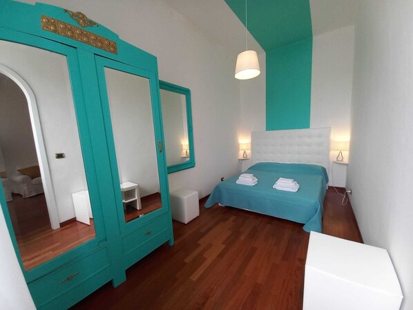 Ein Schlafzimmer mit einem Bett, einem großen Spiegel, einer Kommode und einem Nachttisch.