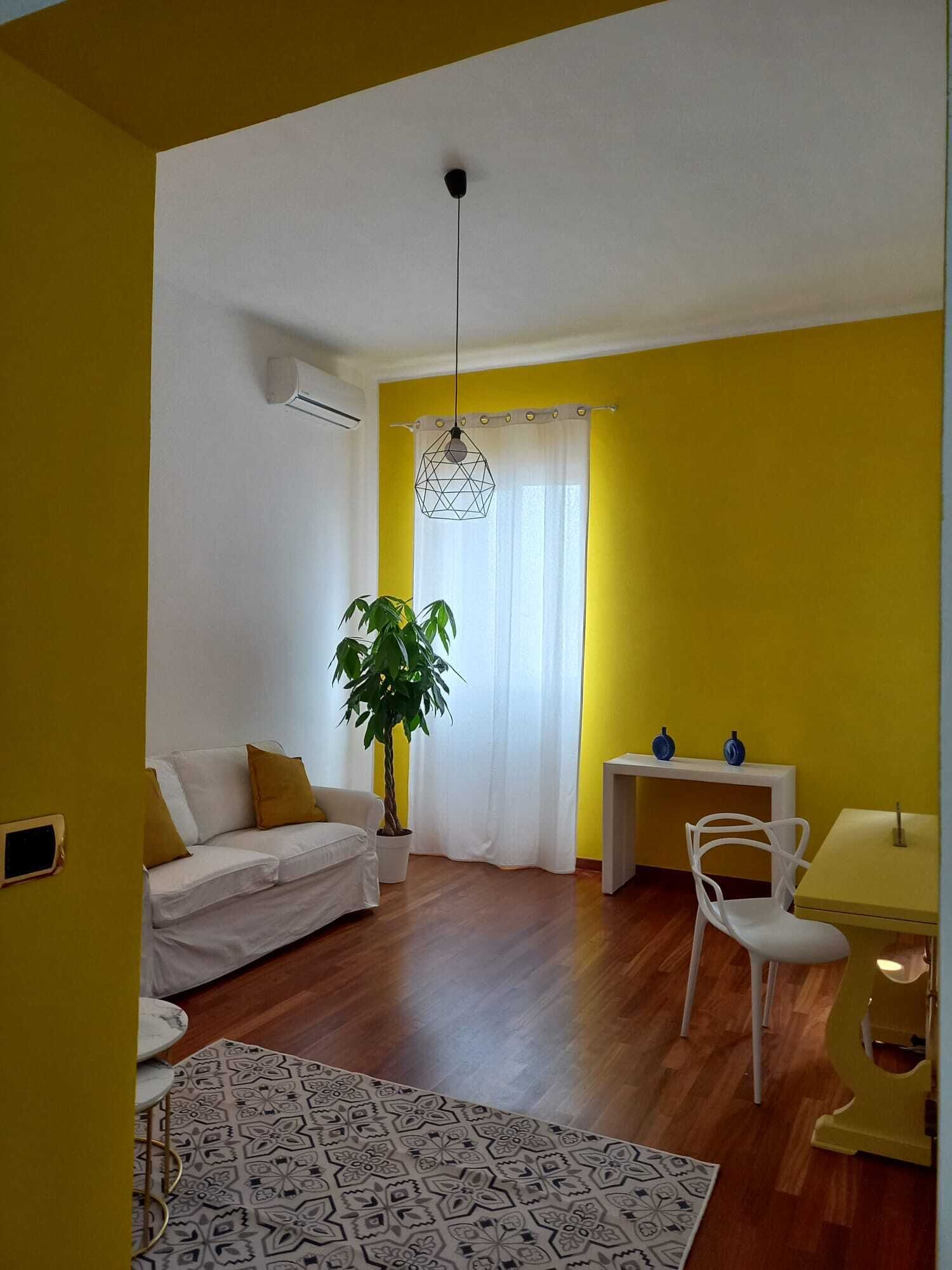 Un salon comprenant un canapé, une table à manger avec des chaises, une plante en pot et un luminaire suspendu.