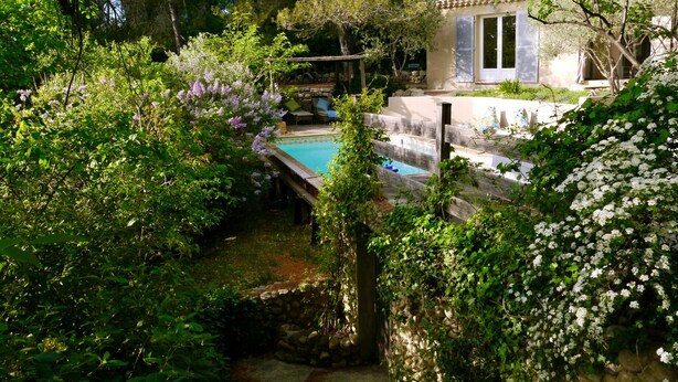A pool surrounded by lush greenery and a stone wall. - Sous L'olivier Avec Piscine Privative (Buisson)