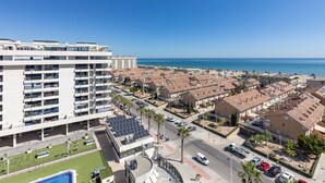 Un quartier résidentiel situé sur la côte, avec des immeubles d’appartements modernes, une route et une vue dégagée sur la mer.