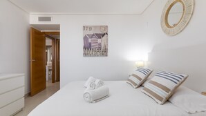 Une chambre d’hôtel avec un lit, deux oreillers, un miroir fixé au mur et un tableau encadré.
