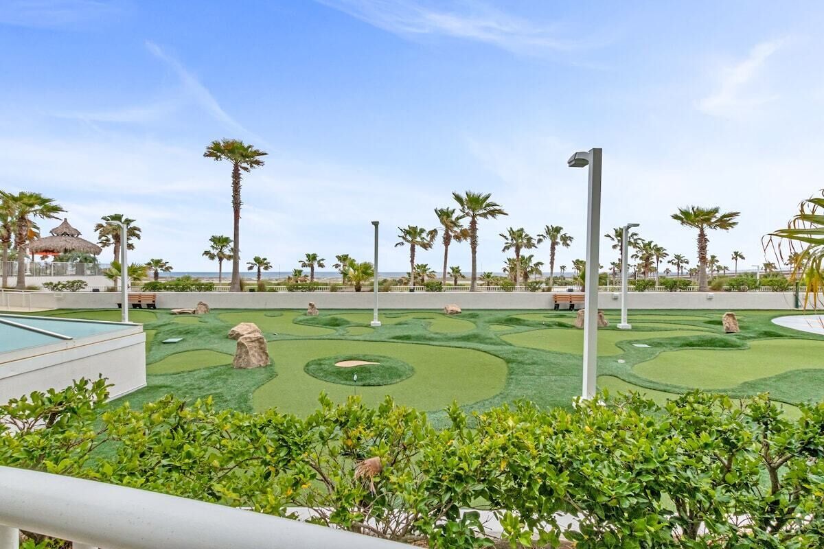 Un parcours de golf doté d’un green d’entraînement, de palmiers et d’un kiosque.