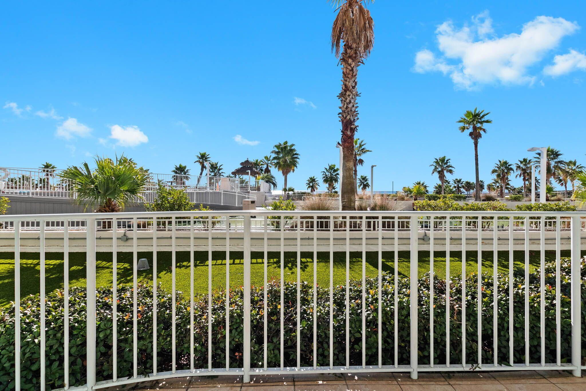 Un jardin clos, agrémenté de palmiers et surplombé d’un ciel d’un bleu limpide.