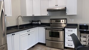 Una cocina moderna con electrodomésticos de acero inoxidable, armarios blancos y encimera negra.