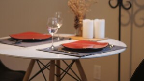 Una mesa de comedor con platos rojos, una copa de vino y velas.