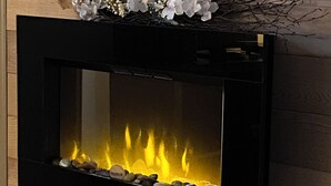 Una chimenea moderna con frente de vidrio, frente a una pared de madera.