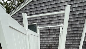 A white wooden structure with a door and a small platform, likely a covered outdoor area or a utility access point. - Cozy Cottage walk to Menauhant Beach (East Falmouth)
