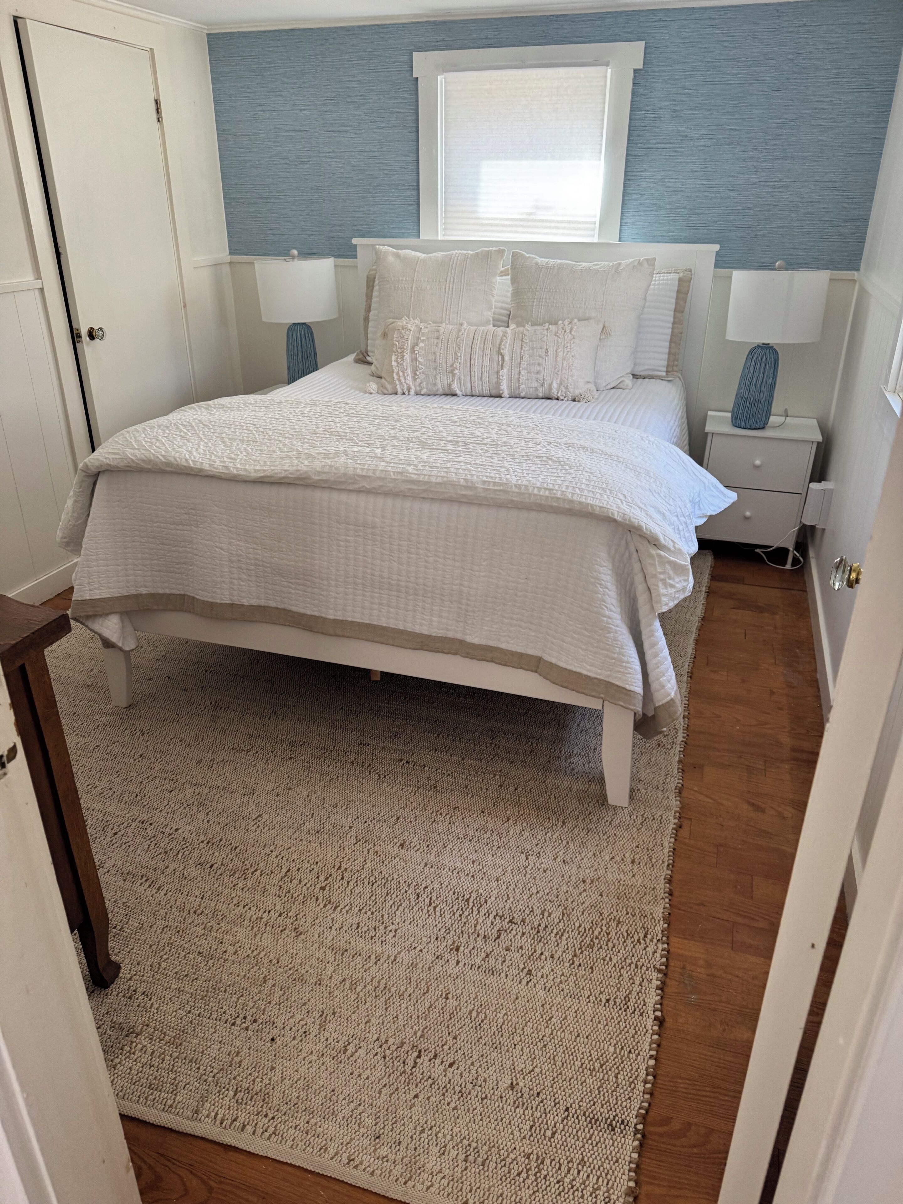 A bedroom with a bed, nightstands, a window, and a door.