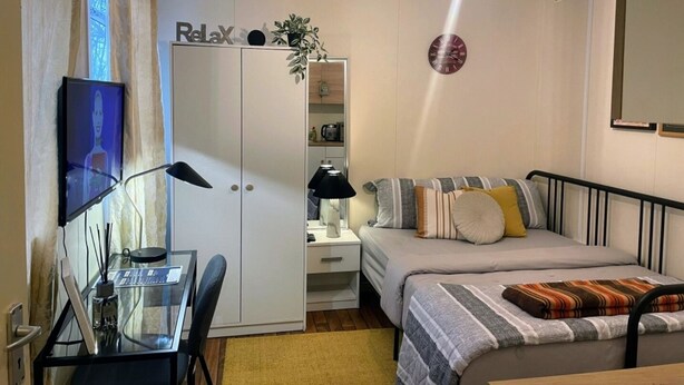 A compact bedroom with a bed, bedside table, lamp, and a TV on a stand. - Ninalodge - Cosy, private self-contained apartment (Letterkenny)