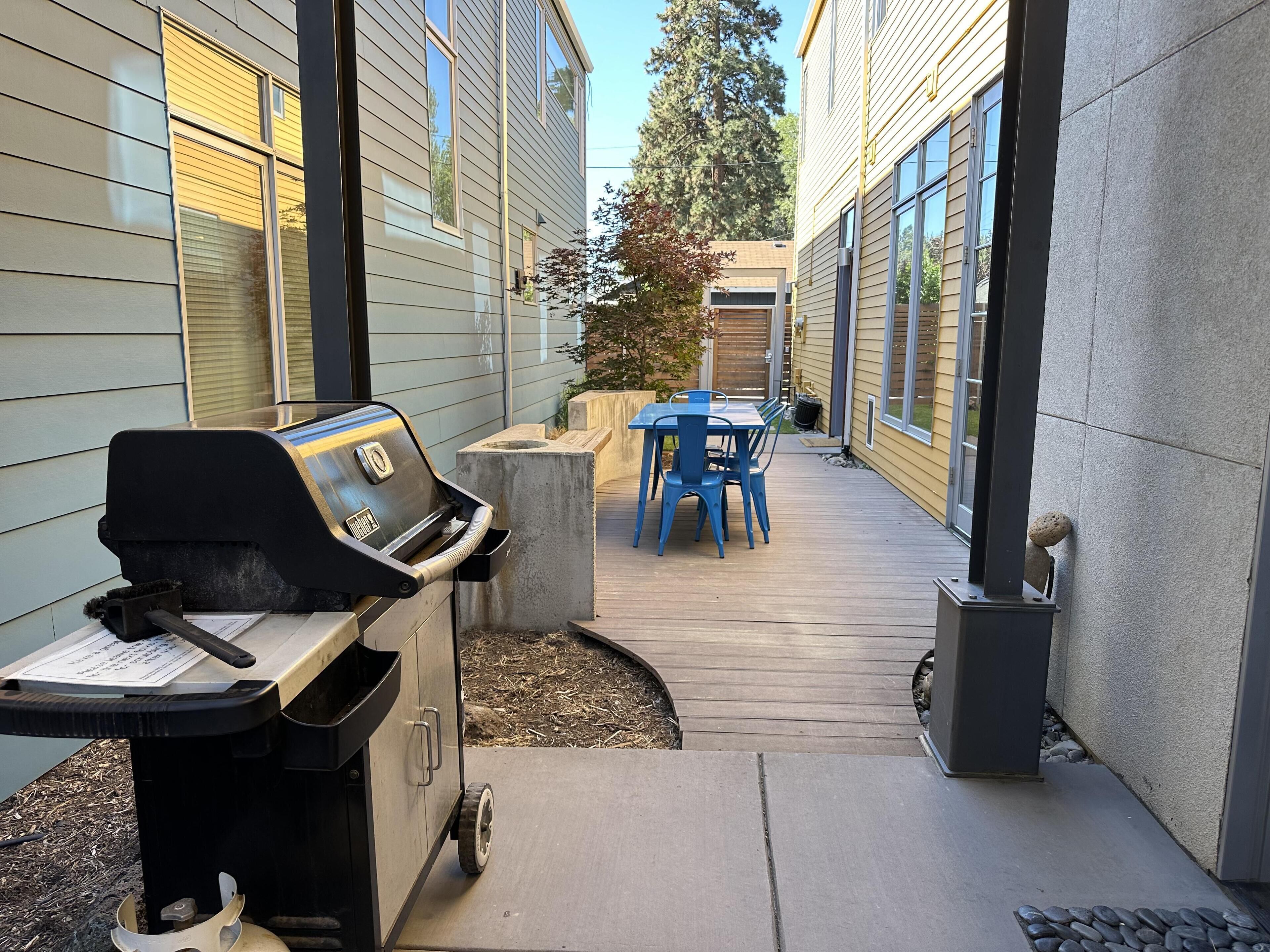 A patio with a grill, a table, and chairs.