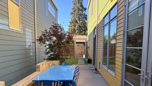 En terrasse med træterrasse, et blåt bord og blå stole.