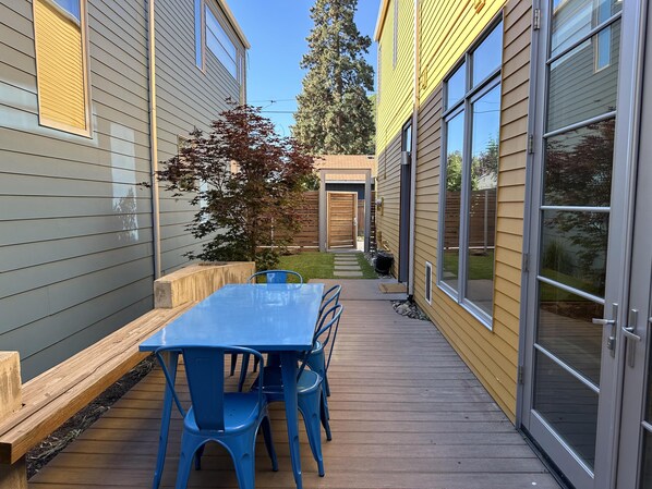 A patio with a wooden deck, a blue table, and blue chairs.