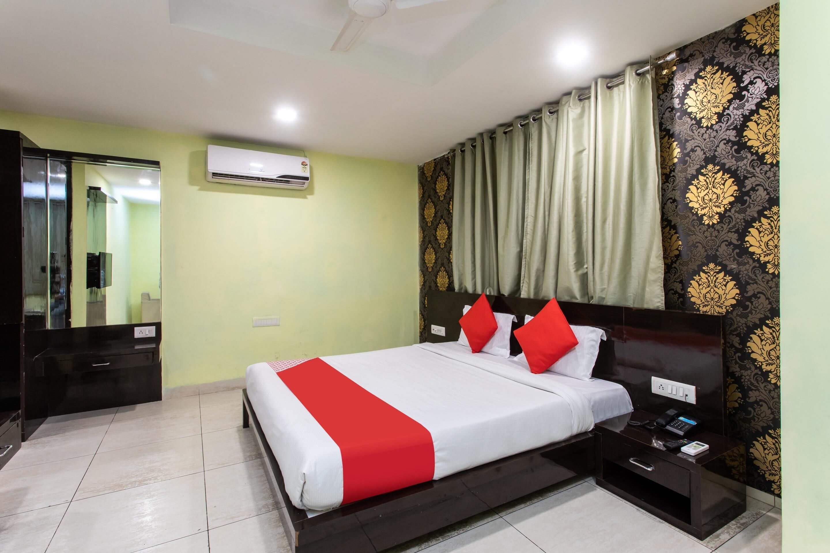 A hotel room with a bed, bedside table, and an air conditioning unit.