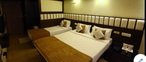 A hotel room with two beds, a nightstand, and a wall-mounted TV.