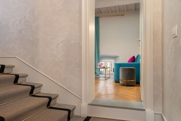 A staircase leading to a room with a teal curtain, a blue sofa, and a small table with a vase of flowers.