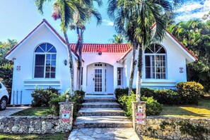 A two-story building with a red-tiled roof, white walls, and a central entrance with a glass door.