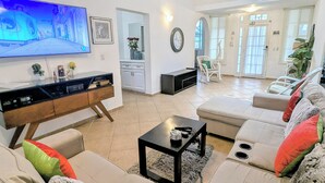 Un salon moderne doté d’un téléviseur à écran plat, d’un canapé, d’une table basse et d’un ventilateur de plafond.