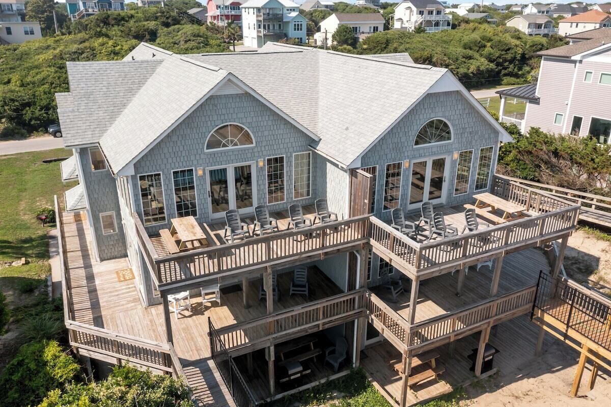 Une maison à plusieurs étages dotée d’une terrasse et d’un espace salon extérieur.