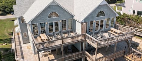 Une maison à plusieurs étages dotée d’une terrasse et d’un espace salon extérieur.