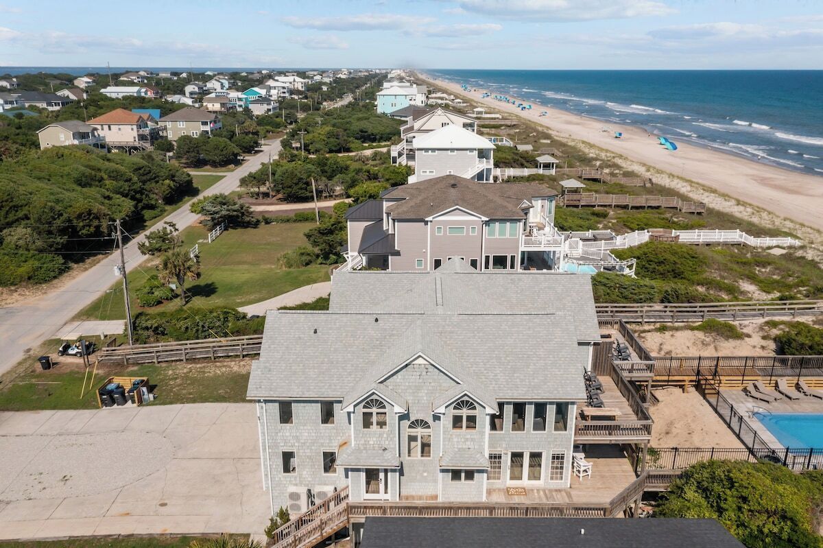 A large two-story house with a balcony overlooking a beach.