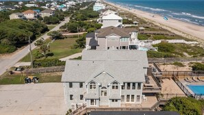 A large two-story house with a balcony overlooking a beach.
