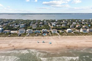 A coastal residential area with houses, a beach, and a view of the ocean.