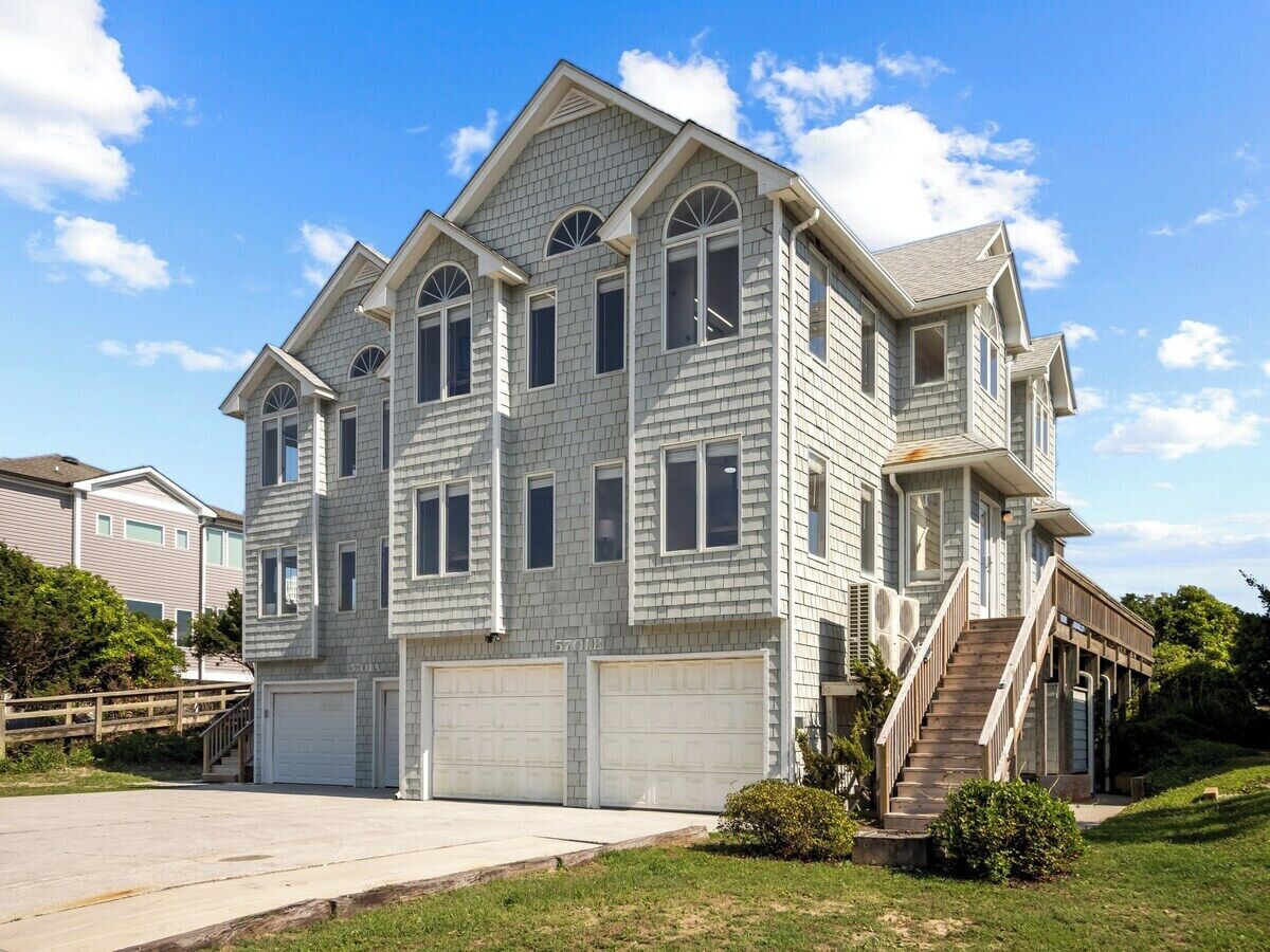 A two-story house with a garage, a staircase leading to the entrance, and a well-maintained lawn.