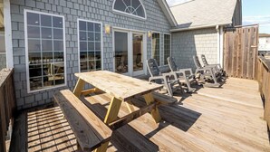 A wooden deck with a picnic table and chairs, a covered area with a window, and a wooden fence.