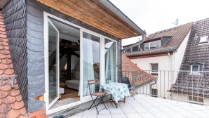 A residential property with a balcony, a table with a tablecloth, and a pair of shoes on the floor. - Attic Apartment at Schlosspark (Wiesbaden)