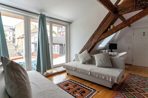 Una sala de estar moderna con un sofá, un tapete estampado y vistas al exterior a través de amplios ventanales.