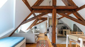 A loft-style bedroom with a bed, a colorful rug, and exposed wooden beams. - Attic Apartment at Schlosspark (Wiesbaden)
