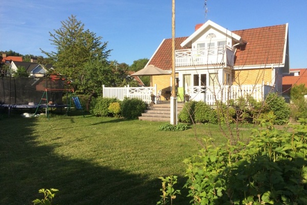 Framsidan med stor trädgård och studsmatta.