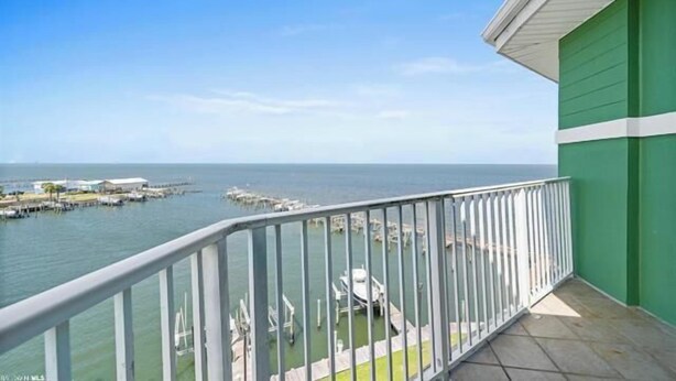 A balcony with a view of the sea and a pier. - Bayfront Bliss: Top-Floor Condo with Stunning Views (Gulf Shores)
