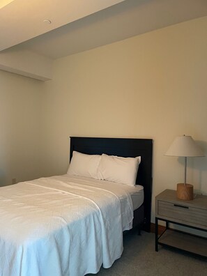Cozy retreat with a single bed, bedside table, and lamp for a functional workspace or reading area.