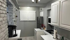 A compact kitchen with white cabinets, a built-in refrigerator, and a sink. - Walk To Goodspeed Opera House! (East Haddam)