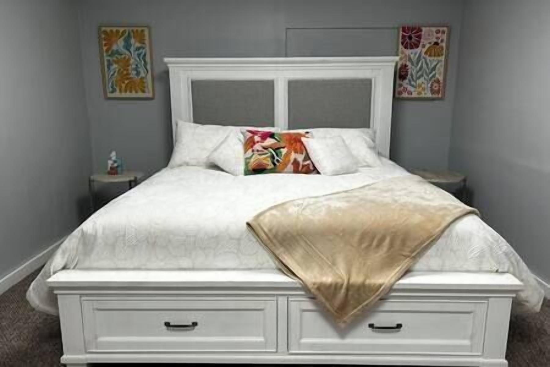 A bed with a white headboard, two bedside tables, and a decorative pillow.