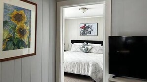 A bedroom with a bed, a television, and a painting of sunflowers. - Walk To Goodspeed Opera House! (East Haddam)