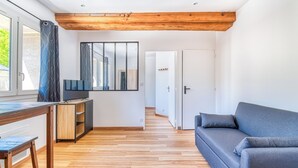 Una sala moderna con un sofá gris, suelo de madera y un travesaño de madera.