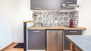 Cocina compacta con encimera de madera, armarios grises y lavavajillas de acero inoxidable.