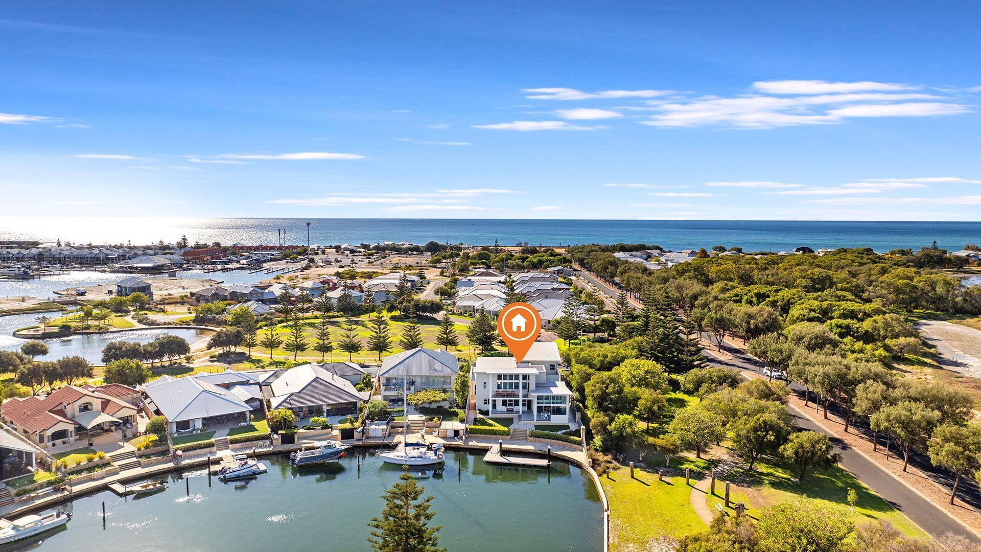 An aerial view of a coastal residential area with houses, a marina, and a large body of water.