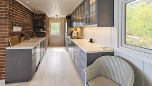 A kitchen with a brick wall, wooden cabinets, and a large window.