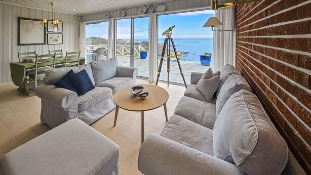 A spacious living room with a large window overlooking a scenic view, a telescope, and a cozy seating arrangement.