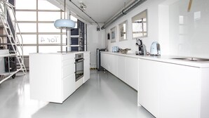 Een moderne keuken met witte kastjes, een centraal eiland met oven, een ingebouwde magnetron en een waterkoker op het aanrecht.