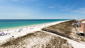 A beach with a wooden boardwalk leading to beachside buildings.