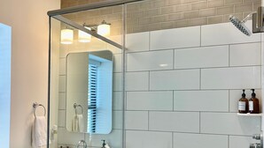 A modern bathroom with a glass-enclosed shower, a large mirror, and a tiled wall. - Modern Fully Renovated Loft in Downtown Trenton (Trenton)