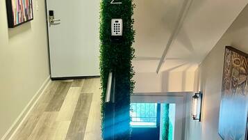 A modern interior with a wooden floor, a staircase, a green vertical garden, and a door marked with the number 2.