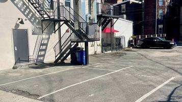 Ein Parkplatz mit Feuerleiter, Mülleimer und einem Gebäude mit roter Markise.